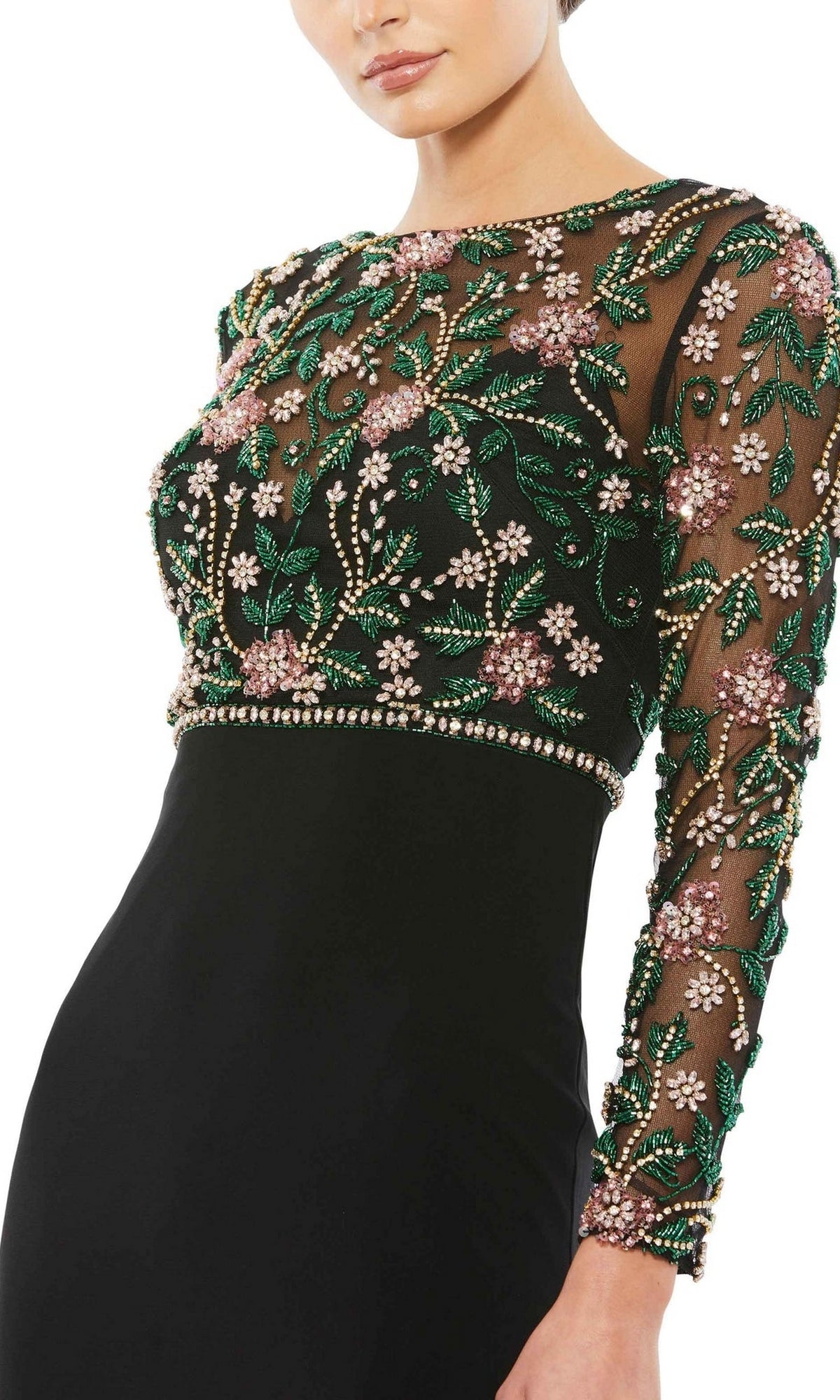 A woman wears the Mac Duggal 67870, a long sleeve black formal dress with a sheer, beaded bodice and sleeves, detailed with green, gold, and pink floral embroidery—an ideal choice for the mother of the bride.